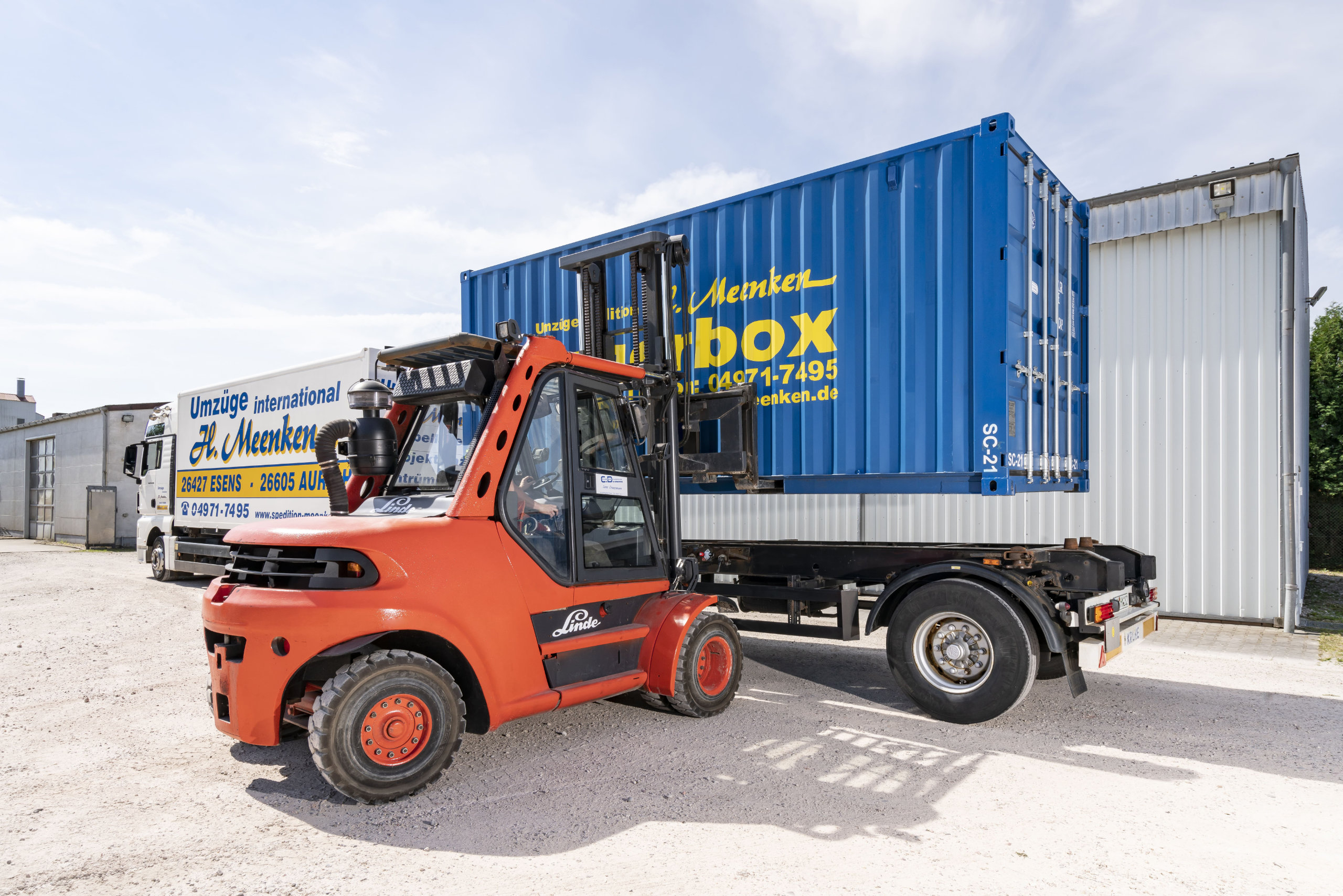 Gabelstapler hebt einen blauen Seecontainer auf einen LKW-Anhänger