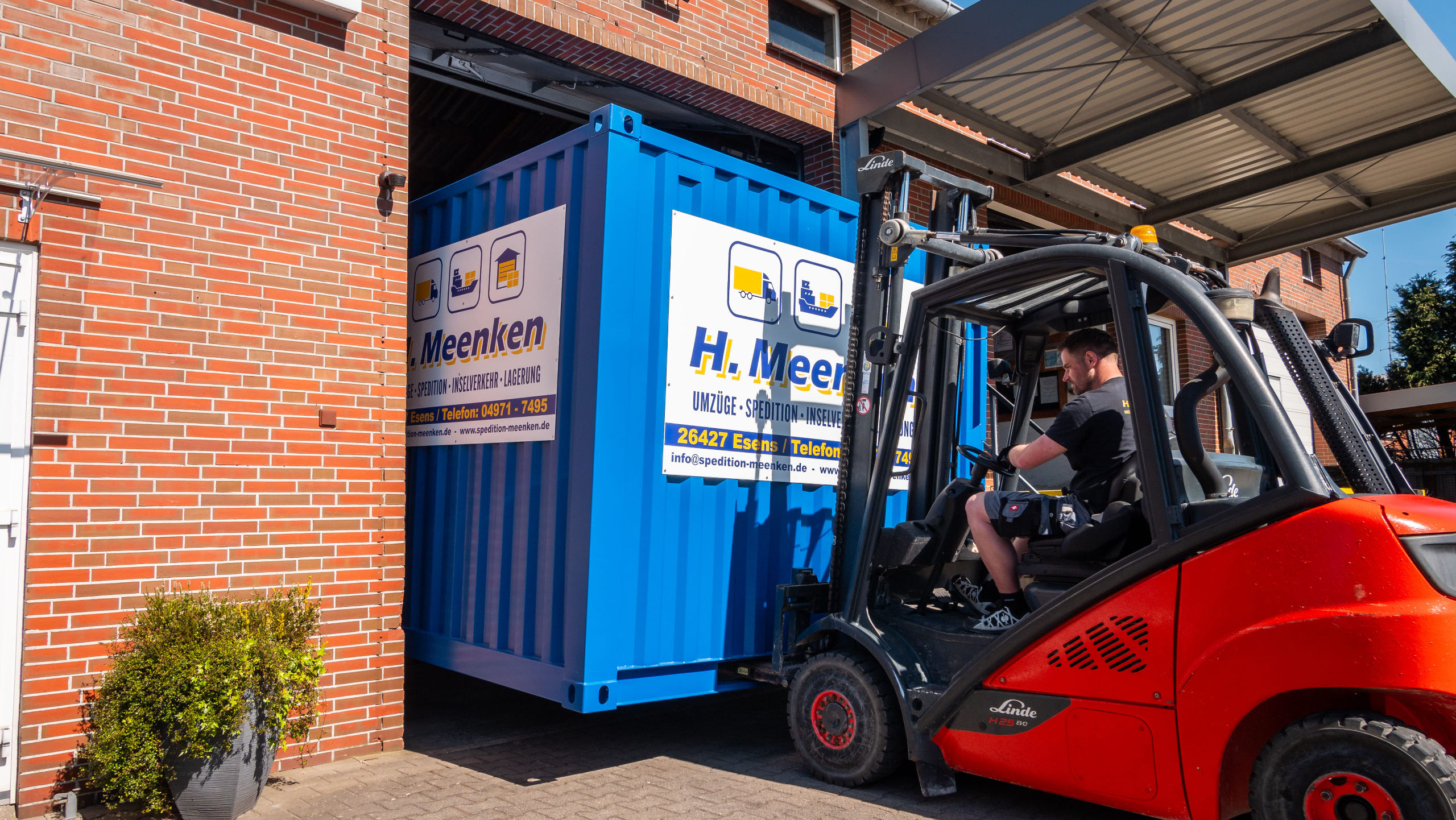Gabelstapler bringt einen blauen Container in das Lagerhaus