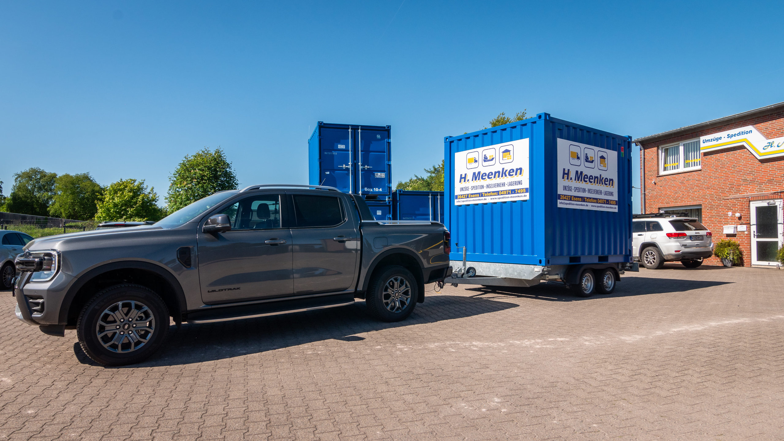 Pick-up der Spedition mit Anhänger worauf ein blauer Container steht