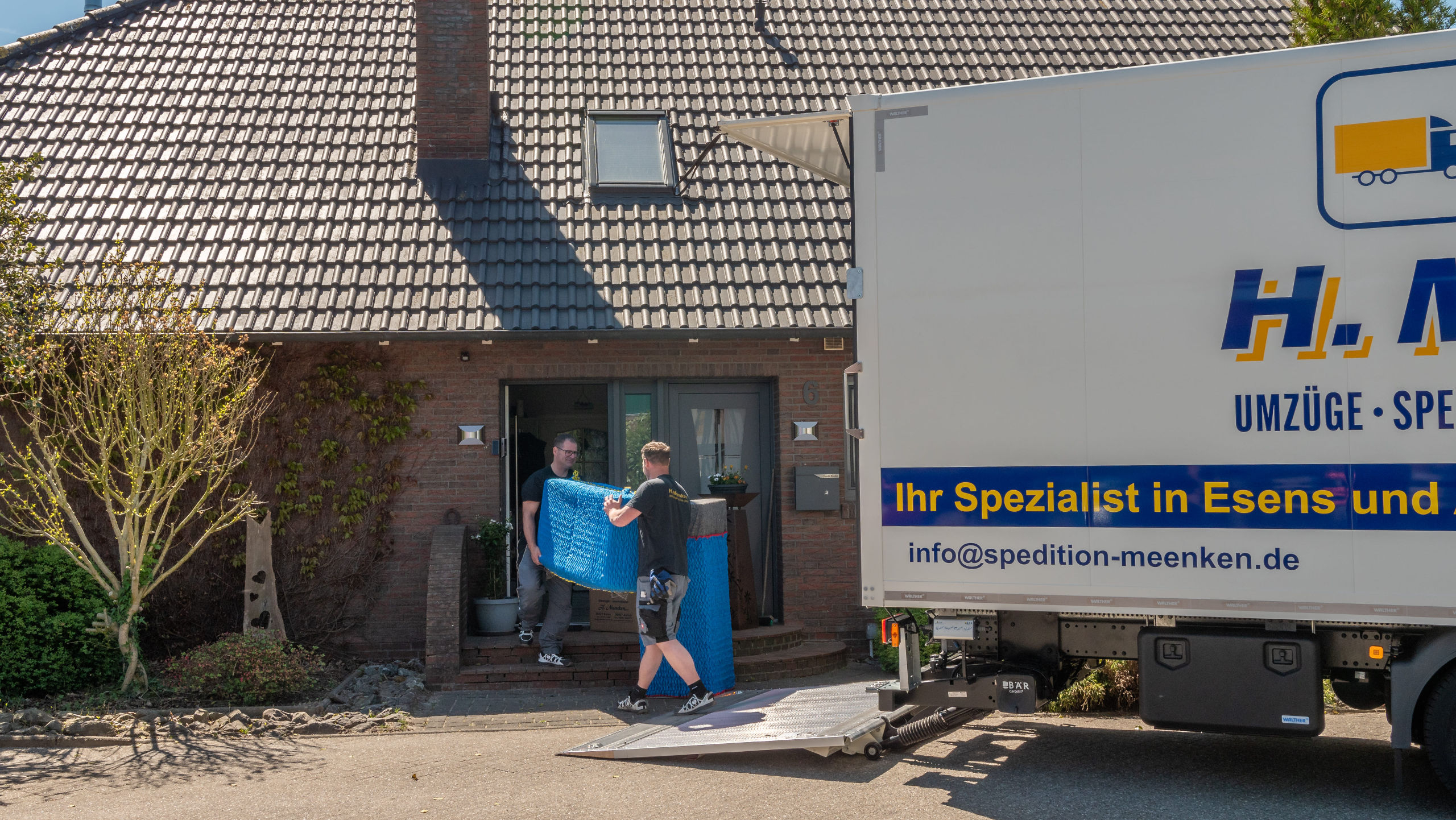 Zwei Mitarbeiter beladen den LKW vor dem Haus